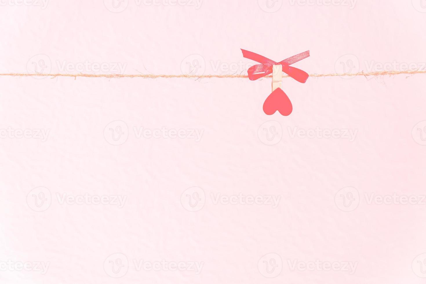 fond d'amour. épingle avec coeur rouge sur un cordon naturel tenant un noeud rouge. photo