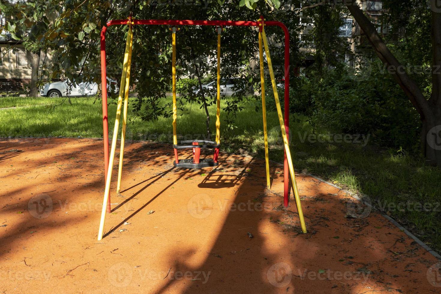 bébé se balance sur une aire de jeux lors d'une journée d'été ensoleillée dans le parc de la ville photo