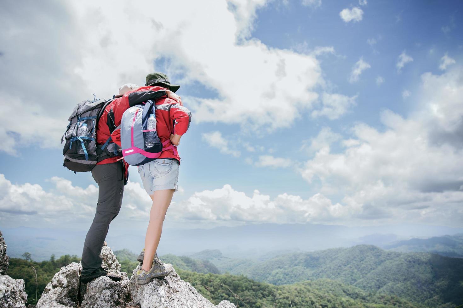 jeune couple de touristes regardant des paysages de montagne spectaculaires en haute montagne. randonneur homme et femme sur le rocher supérieur. un couple de voyageurs amoureux. les gens saluent l'aube. les amoureux voyagent. copie espace photo