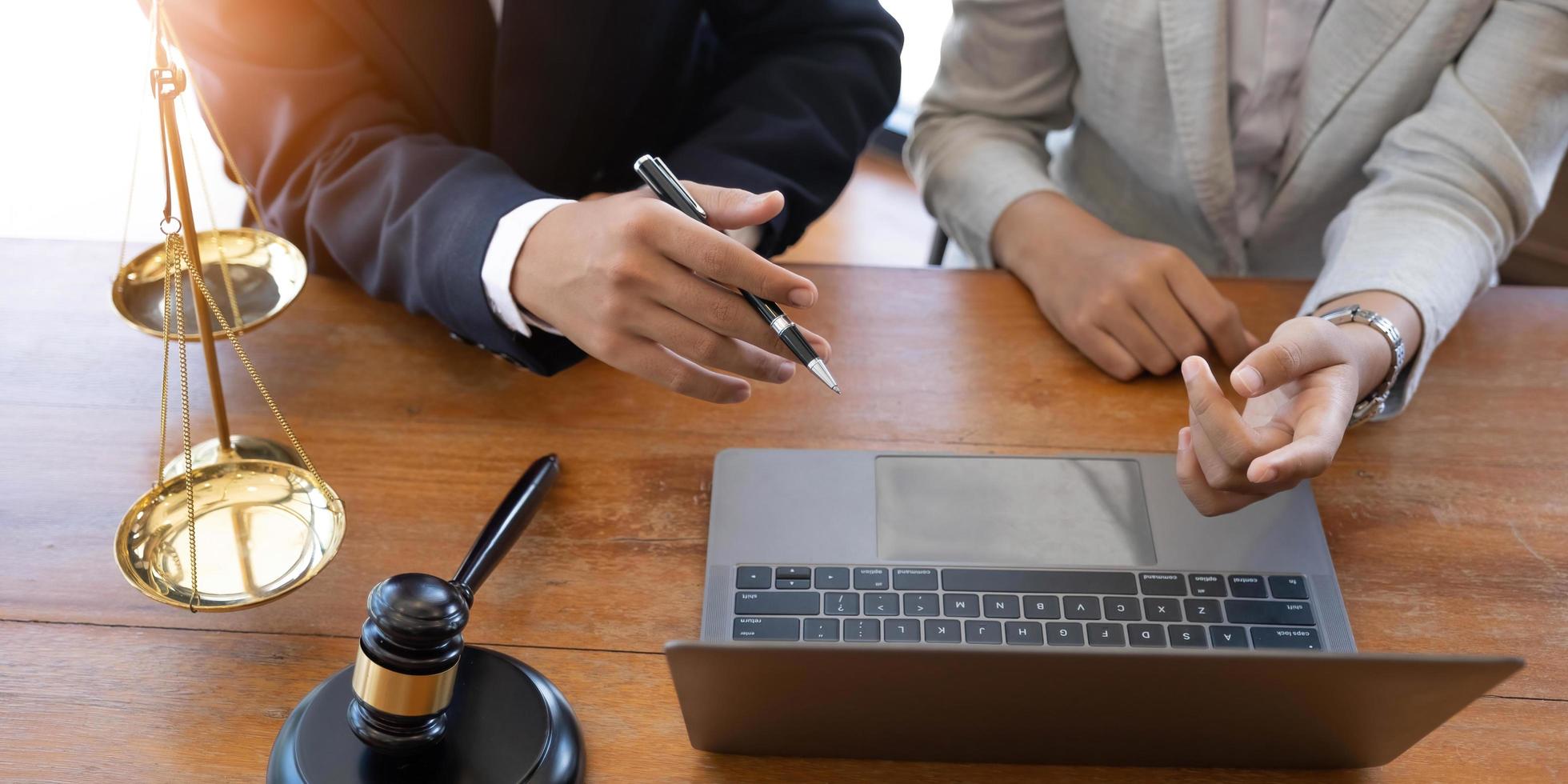 les avocats notaires ou les juges consultent ou discutent des documents contractuels avec des clients commerciaux au bureau. concept de services juridiques et juridiques avec marteau et balance avec un ordinateur portable sur la table. photo