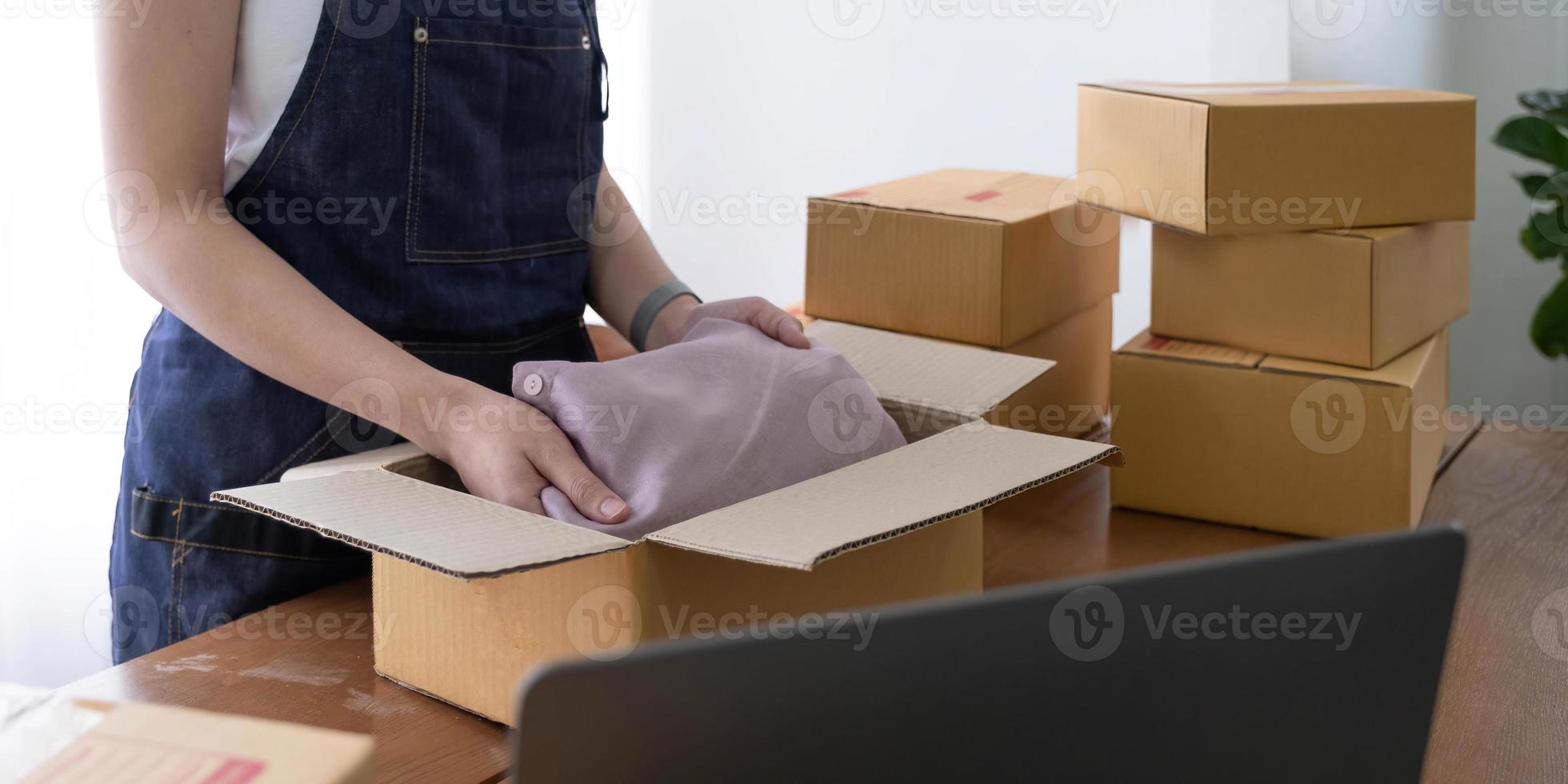 démarrage petite entreprise entrepreneur PME, femme asiatique emballant la chemise dans la boîte. portrait jeune propriétaire de petite entreprise asiatique bureau à domicile, livraison de marketing de vente en ligne, concept d'emploi de télémarché de commerce électronique PME photo