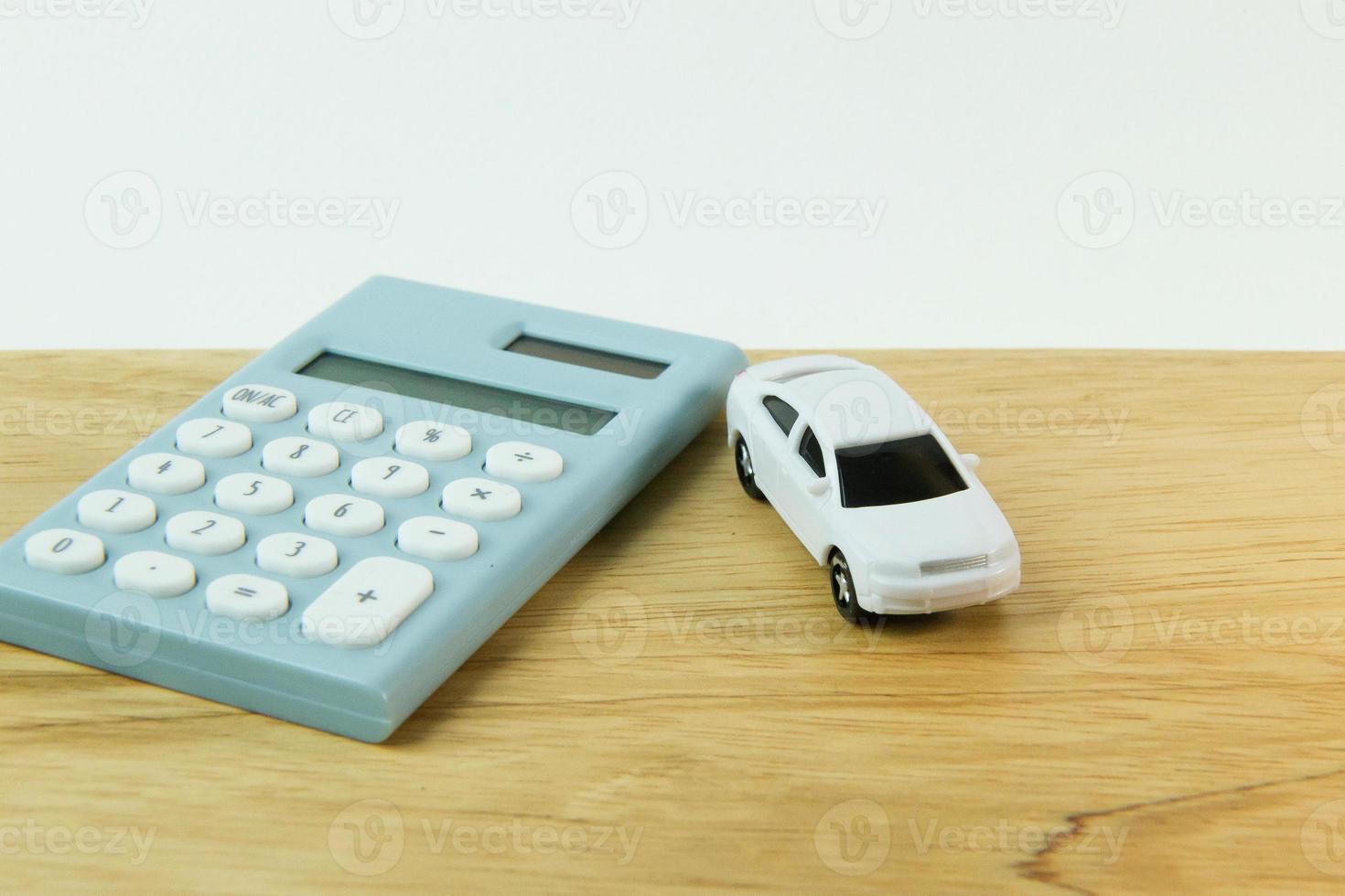 jouet de voiture blanche et calculatrice bleu fond blanc. photo