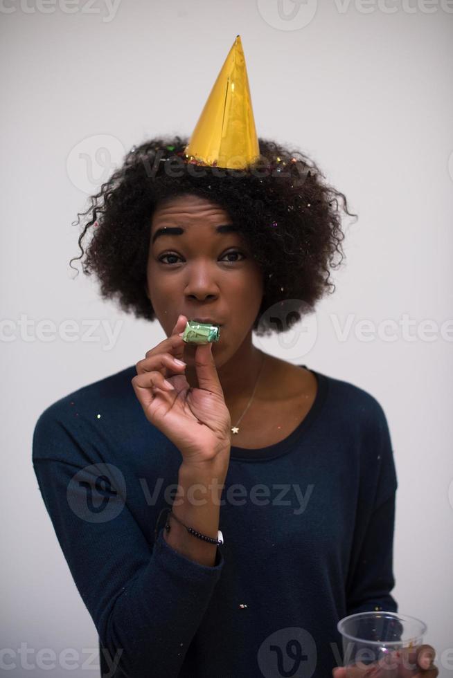 femme noire en chapeau de fête soufflant dans un sifflet photo