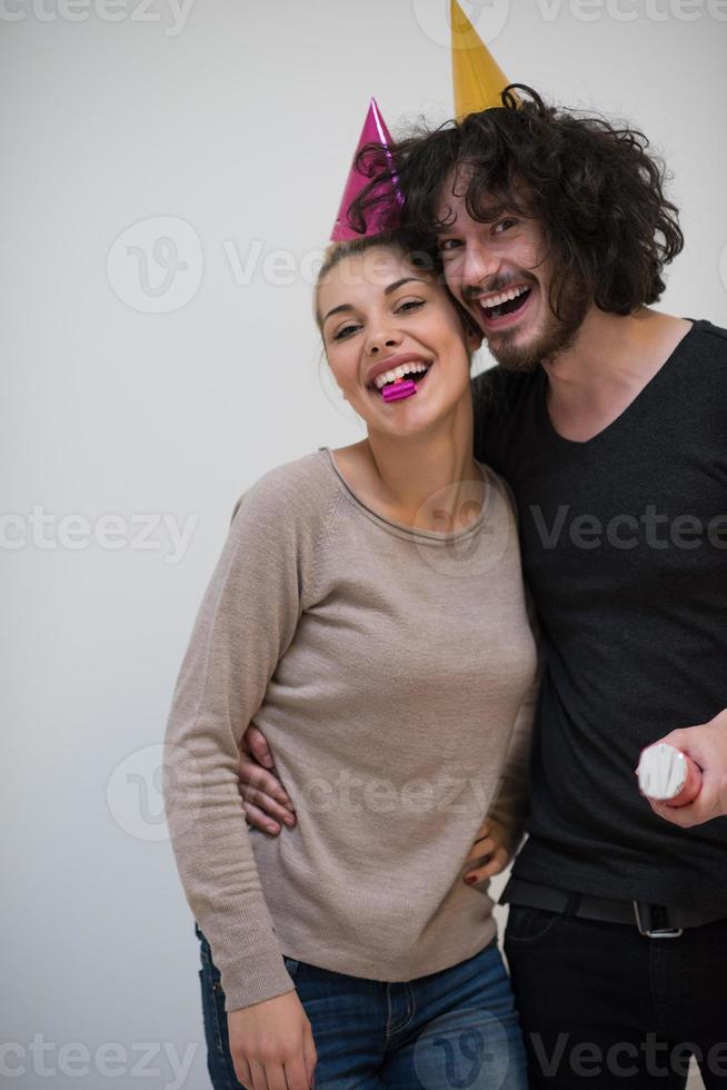 couple en chapeaux de fête soufflant dans un sifflet photo