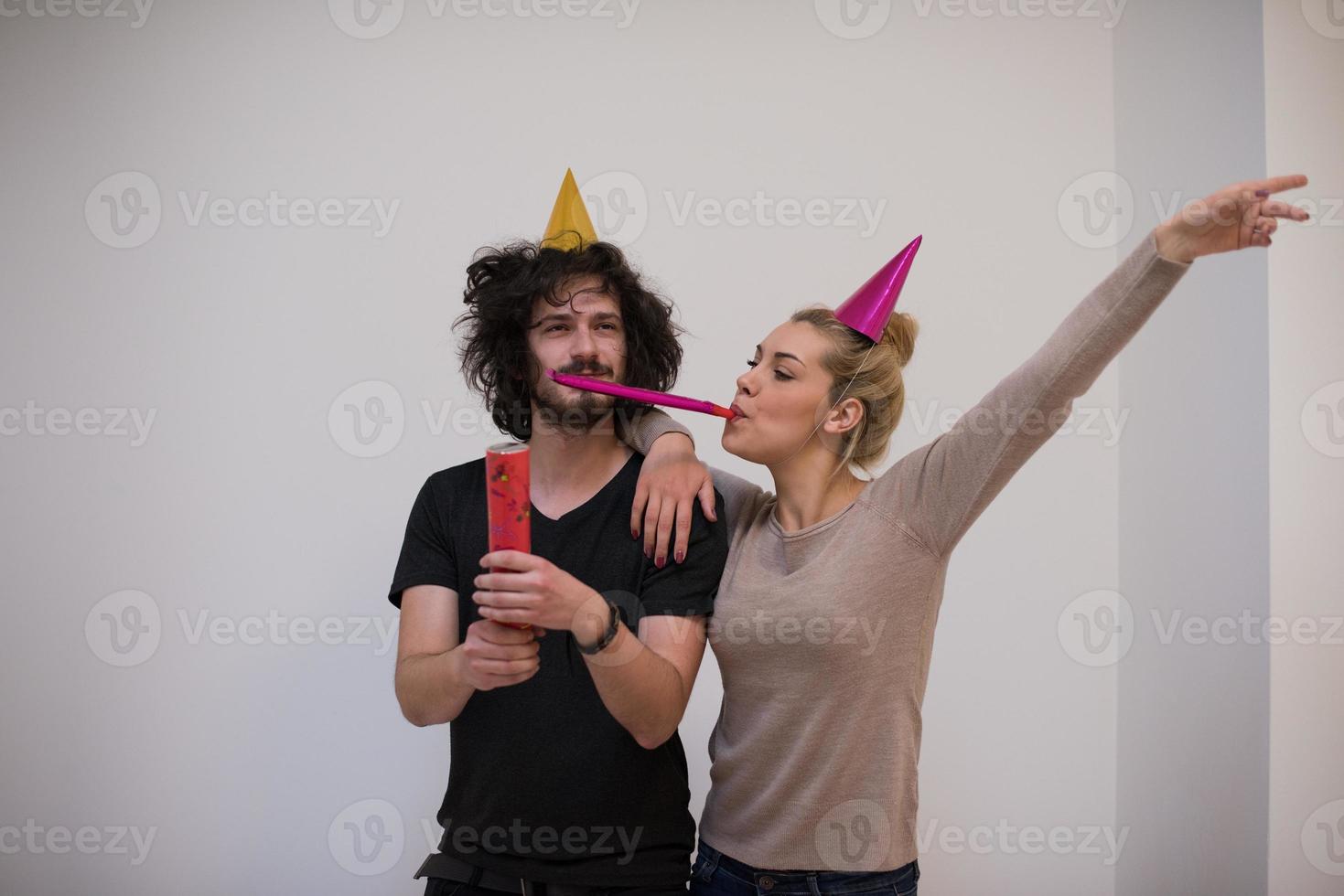 couple en chapeaux de fête soufflant dans un sifflet photo