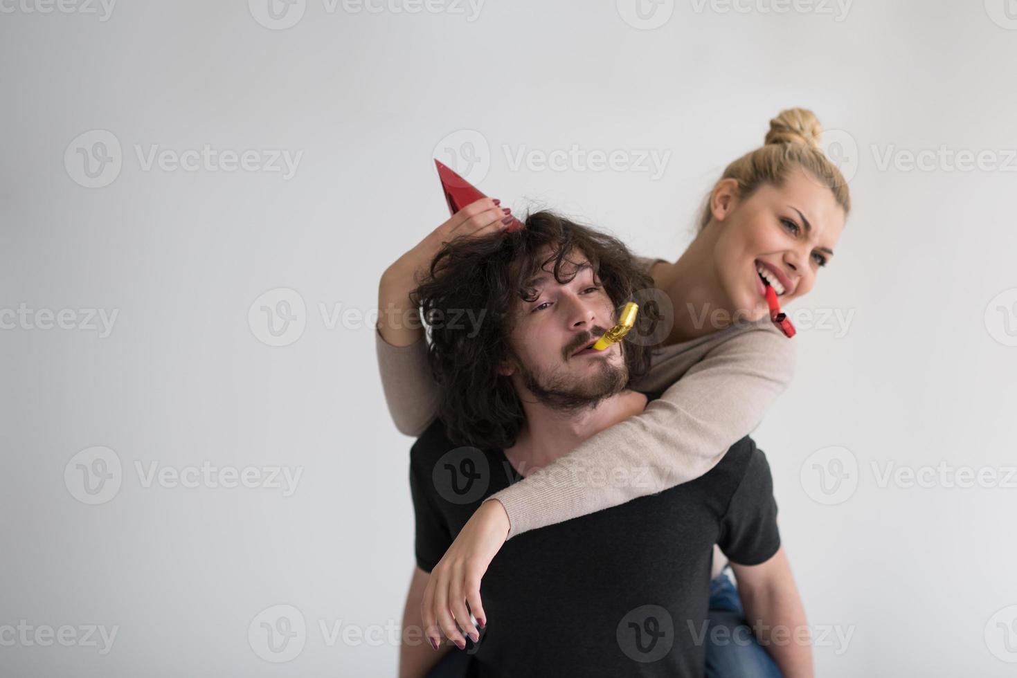 couple en chapeaux de fête soufflant dans un sifflet photo
