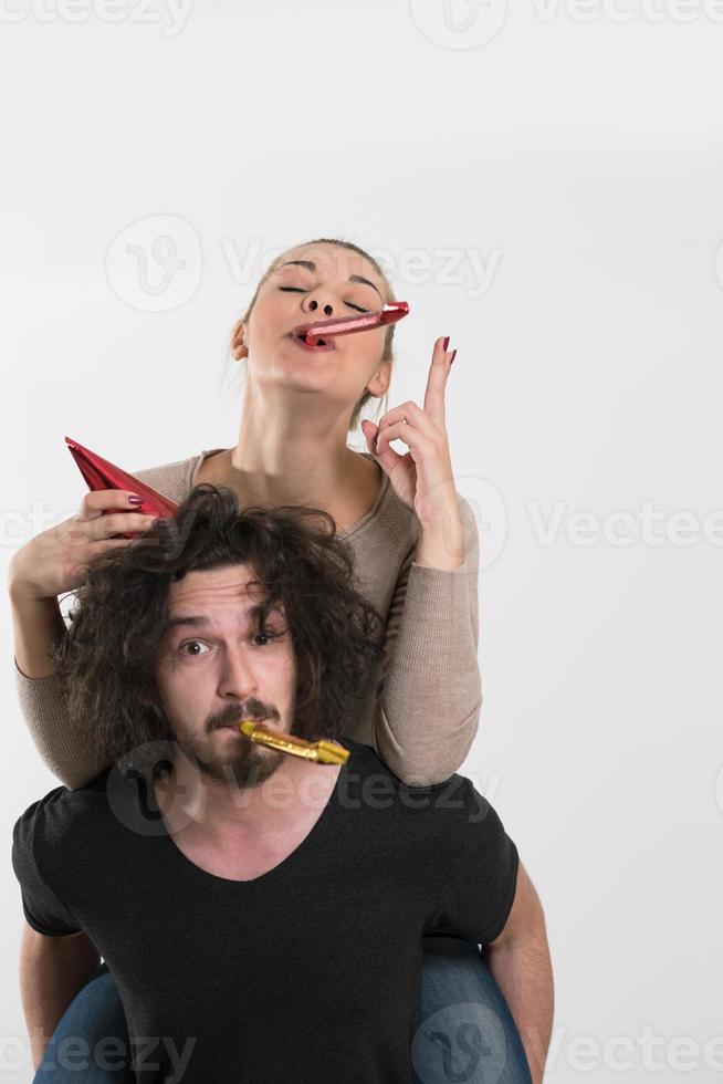 couple en chapeaux de fête soufflant dans un sifflet photo