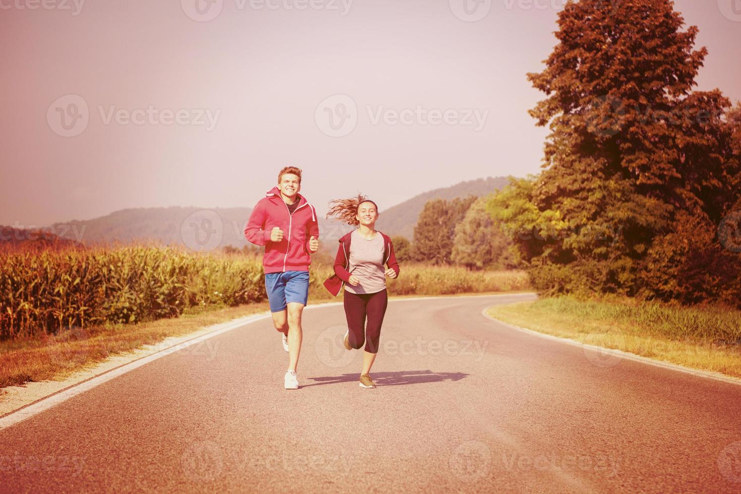 jeune couple faisant du jogging le long d'une route de campagne photo