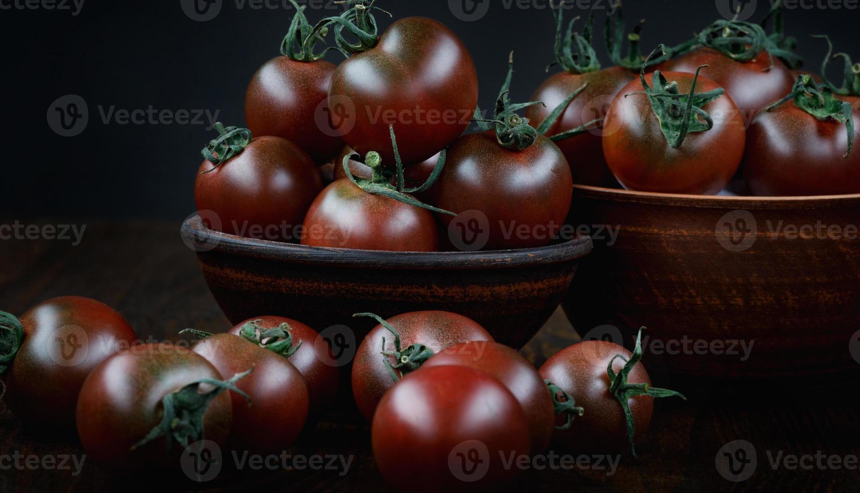 beaucoup de tomates juteuses mûres sur fond noir. tomates cerises. photo