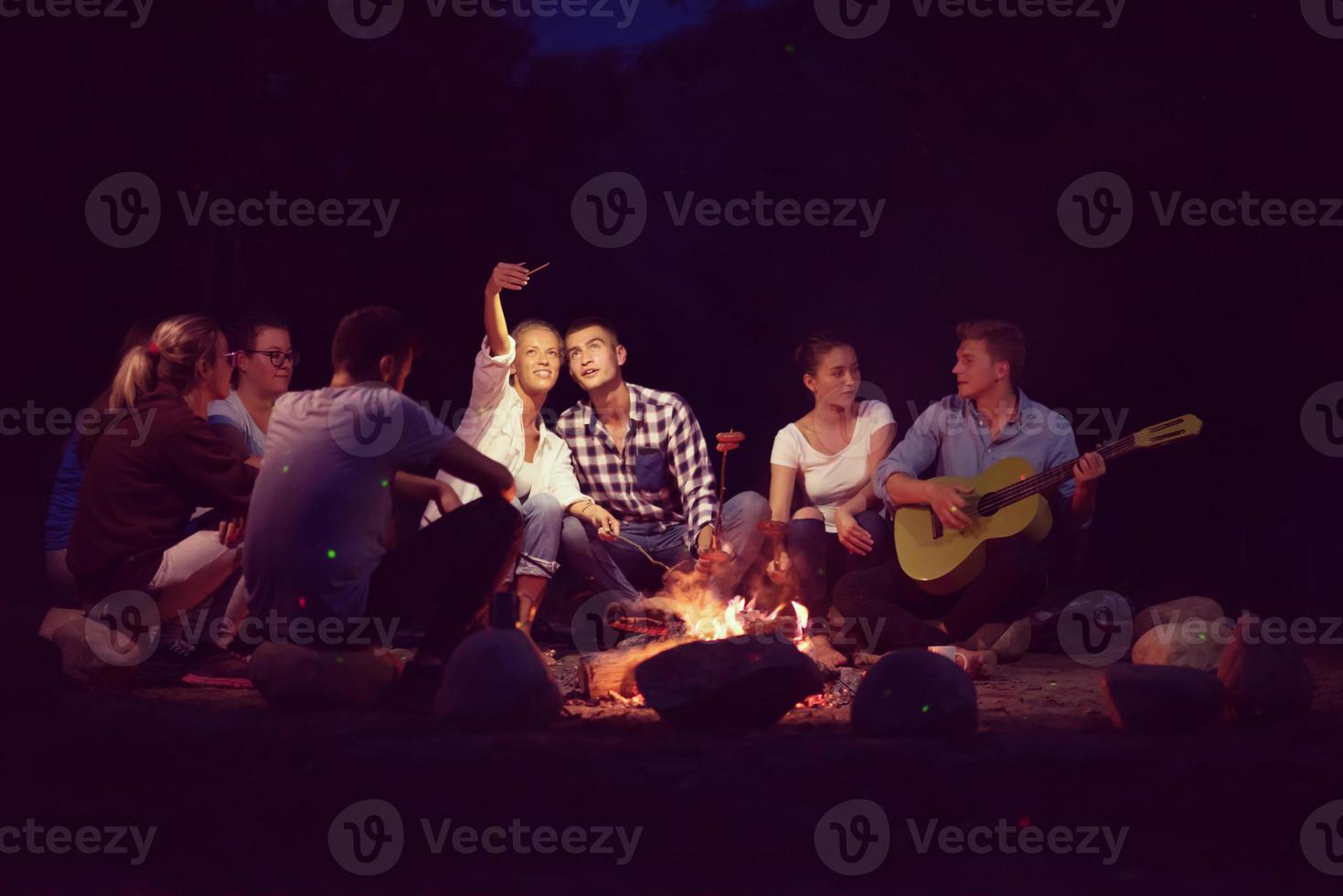 jeunes amis se détendant autour d'un feu de camp photo