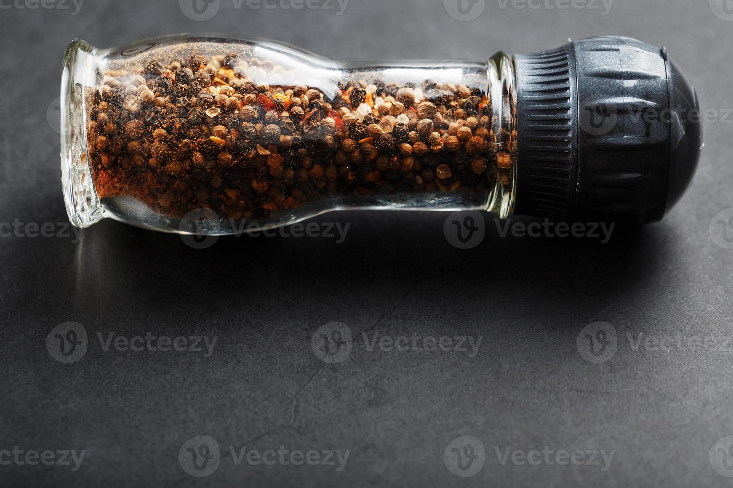 mélange d'assaisonnement dans un moulin à verre sur fond noir photo