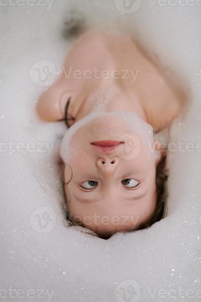 petite fille dans le bain jouant avec de la mousse de savon photo