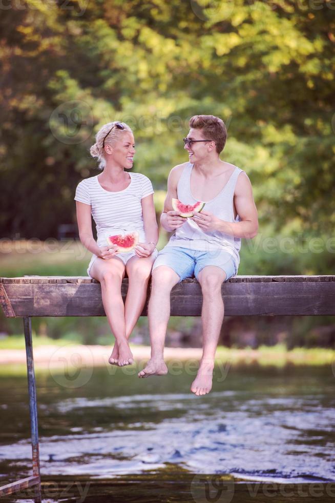 couple profitant de la pastèque assis sur le pont en bois photo