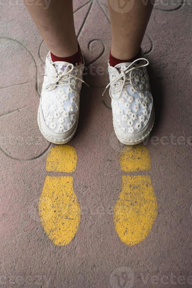 pieds et flèches sur la route. signe de flèche droite jaune et chaussures blanches. concept de direction droite. notion de voyage photo