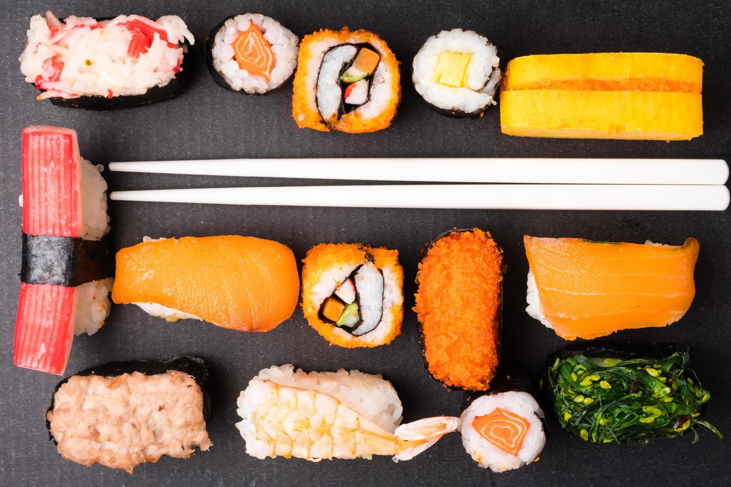 vue de dessus du jeu de sushis et des baguettes sur fond noir, cuisine japonaise. photo