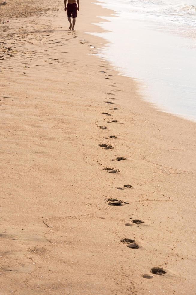 empreintes de pas d'un homme marchant sur la plage. notion de voyage photo