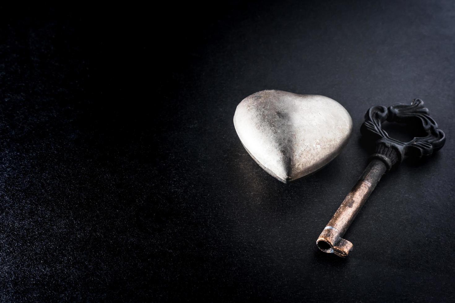 coeur en métal avec clé sur fond sombre, concept d'amour de métaphore. photo