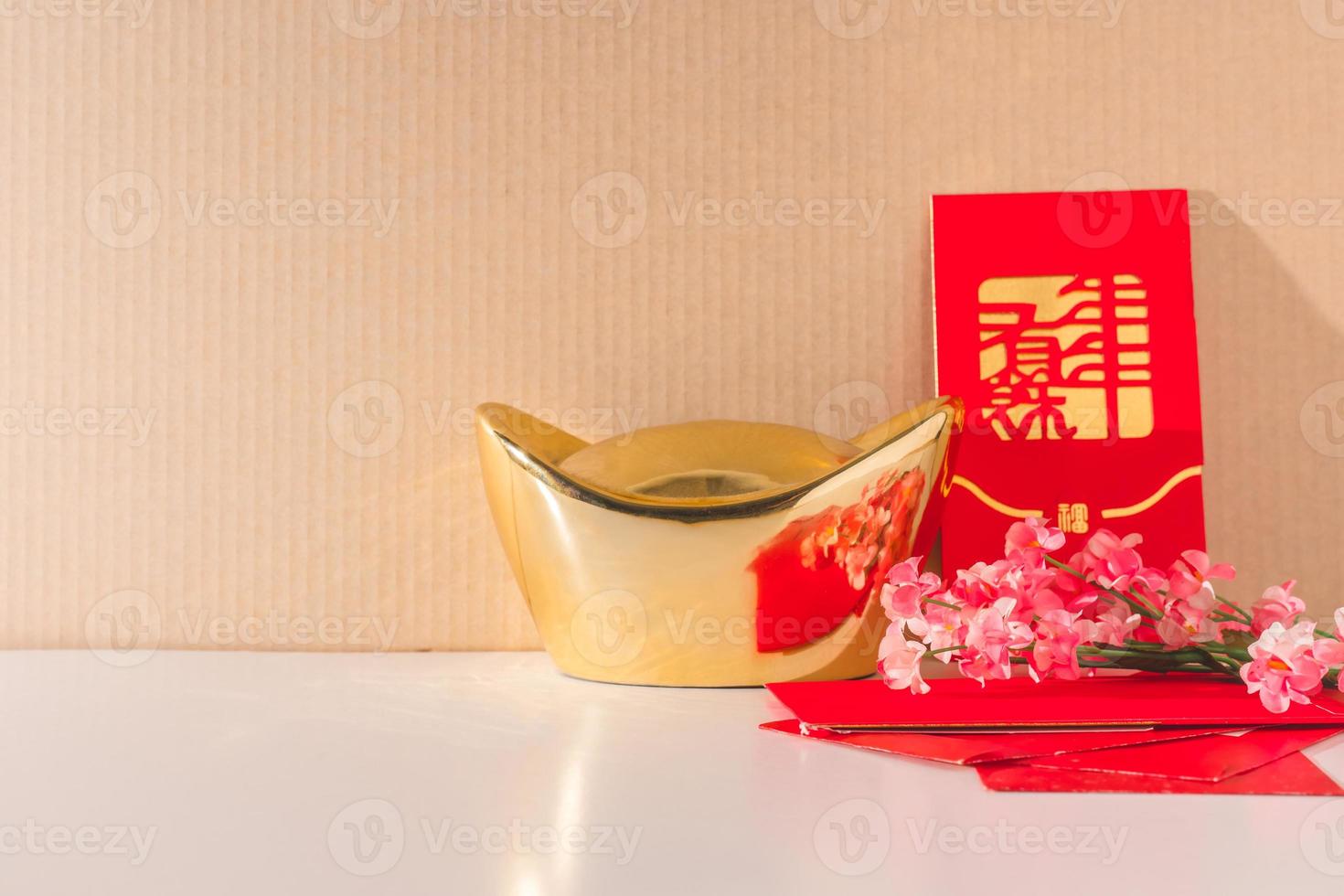 lingots d'or chinois avec des paquets rouges et des fleurs de prunier chinois sur la table photo