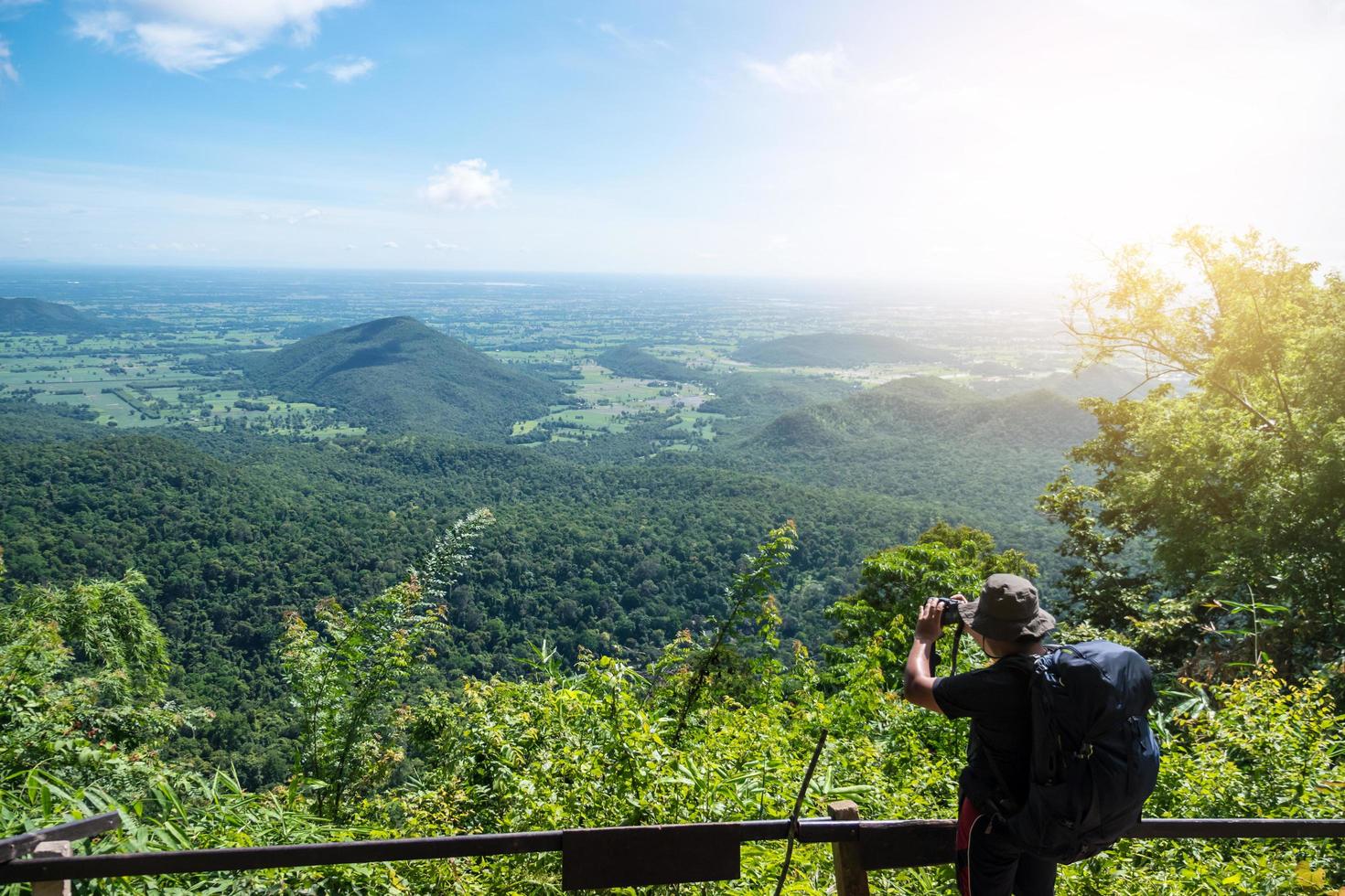 homme voyageur prenant une photo au sommet de la montagne avec un ciel bleu.