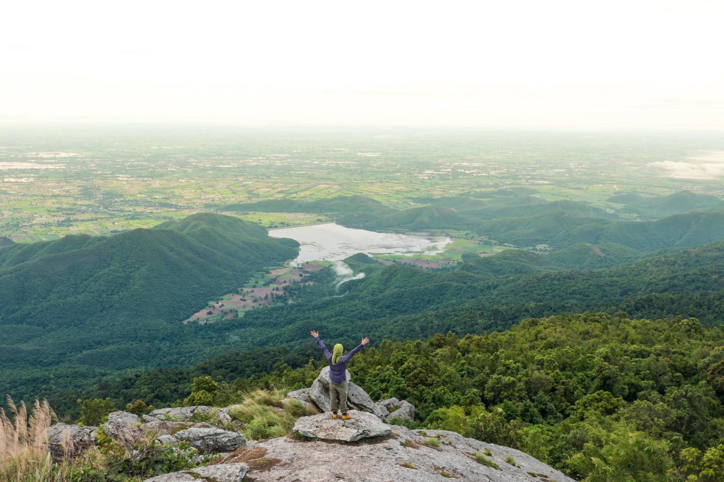 jeune homme profitant d'une vue sur la vallée du haut d'une montagne. photo