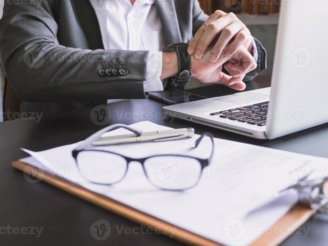 gros plan sur un homme d'affaires travaillant sur le bureau et vérifiant l'heure sur sa montre-bracelet. photo