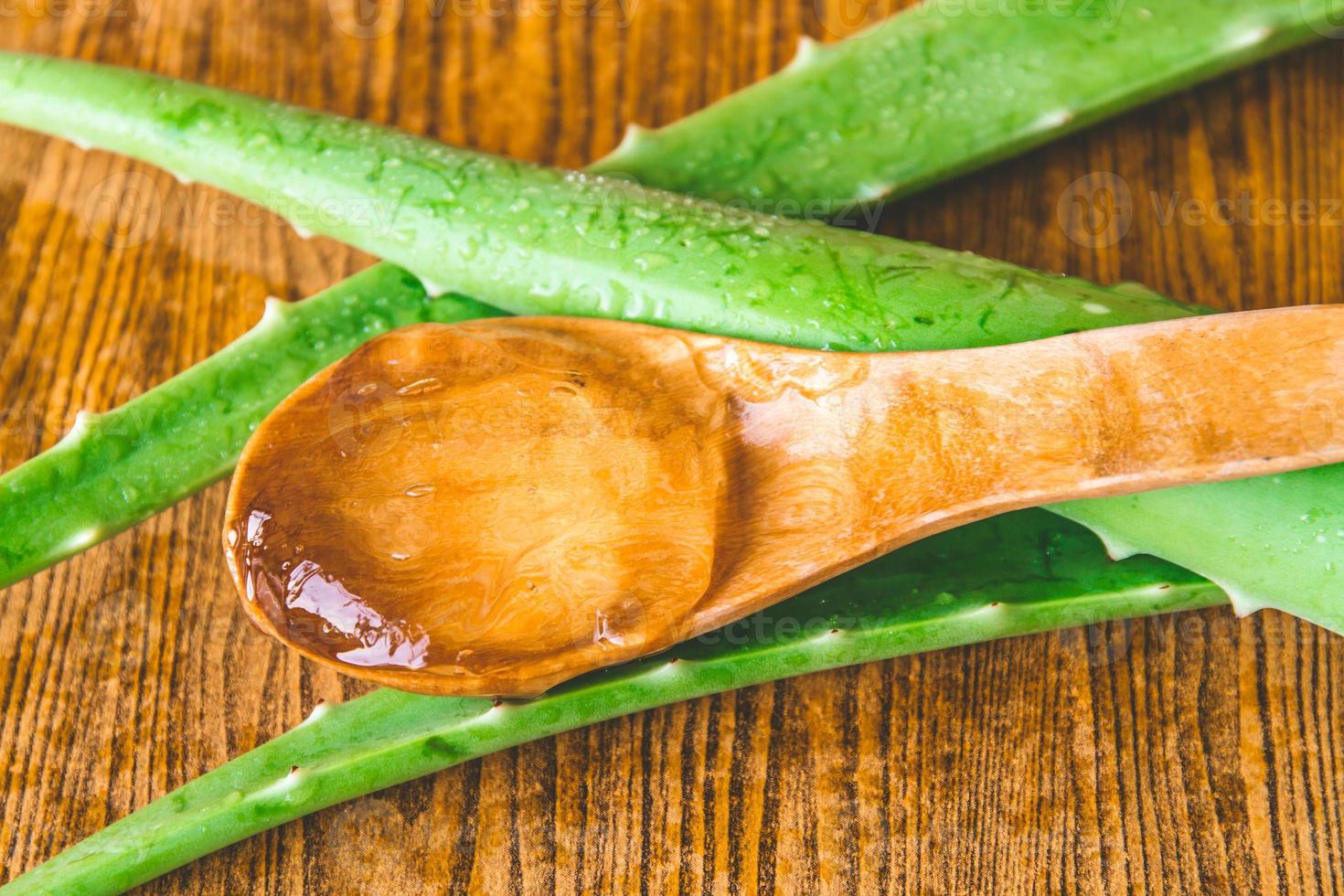 gros plan de gel d'aloe vera sur une cuillère en bois avec de l'aloe vera sur une table en bois. photo