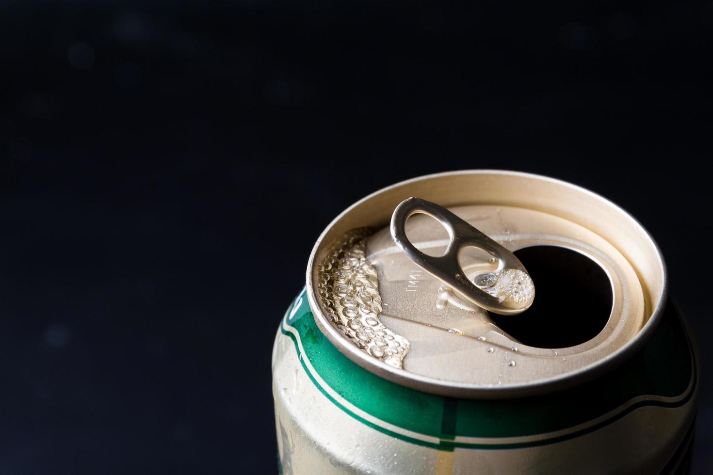 gros plan d'une canette de bière ouverte sur fond noir. photo