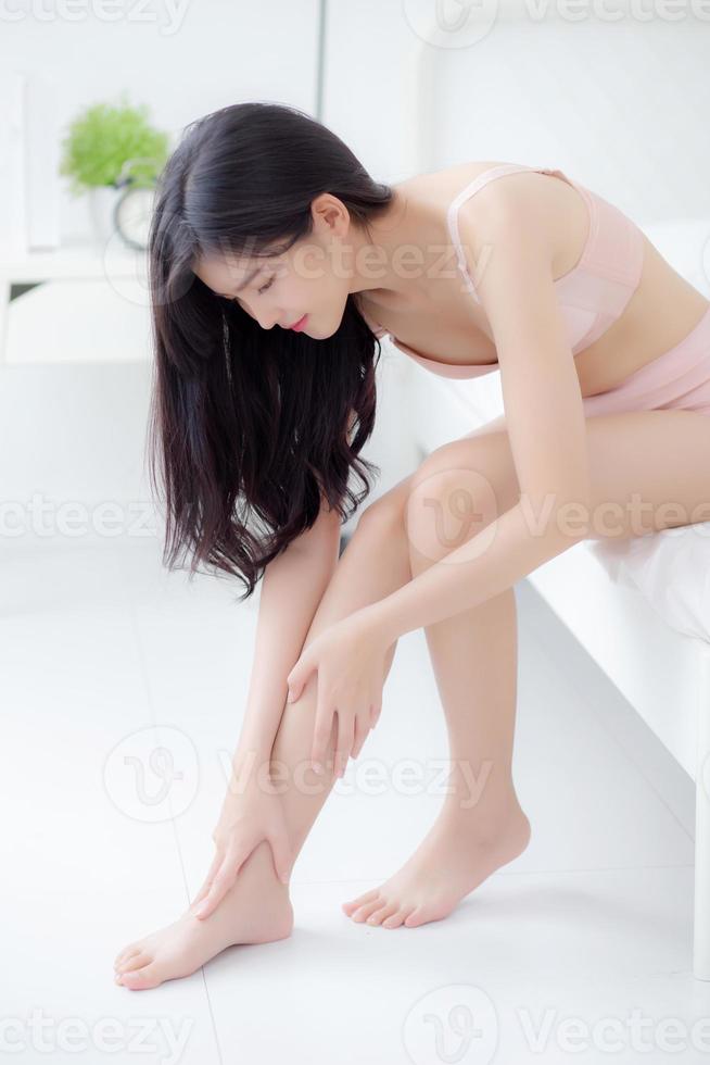 jeune femme asiatique touche la peau de la jambe lisse avec de la crème et de la lotion pour l'hydratation et la douceur, fille appliquant des soins du corps et des cosmétiques pour une beauté soyeuse et douce, parfaite avec le bien-être, la santé et les soins. photo