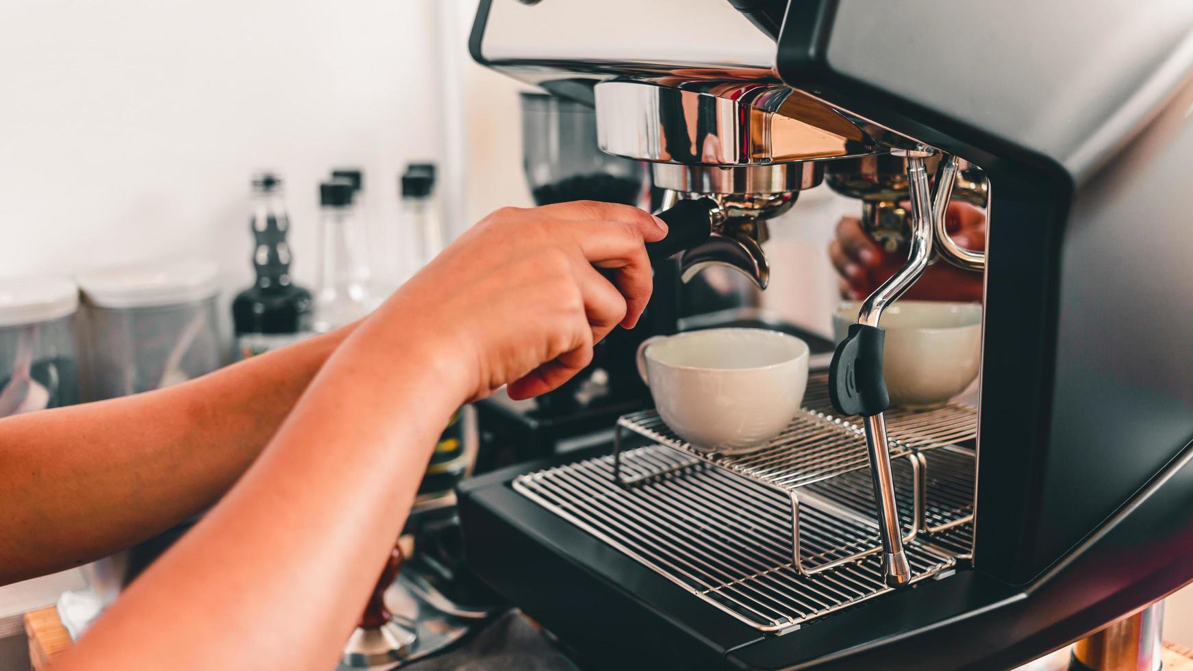 barista attachant un porte-filtre à l'appareil café pour faire du café pour les clients dans le café. concept de service de préparation de café photo