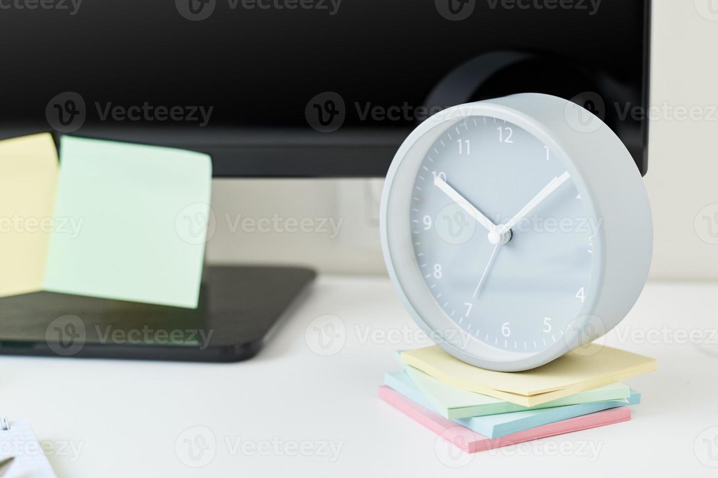 lieu de travail avec une horloge, des fournitures de bureau et des notes autocollantes photo