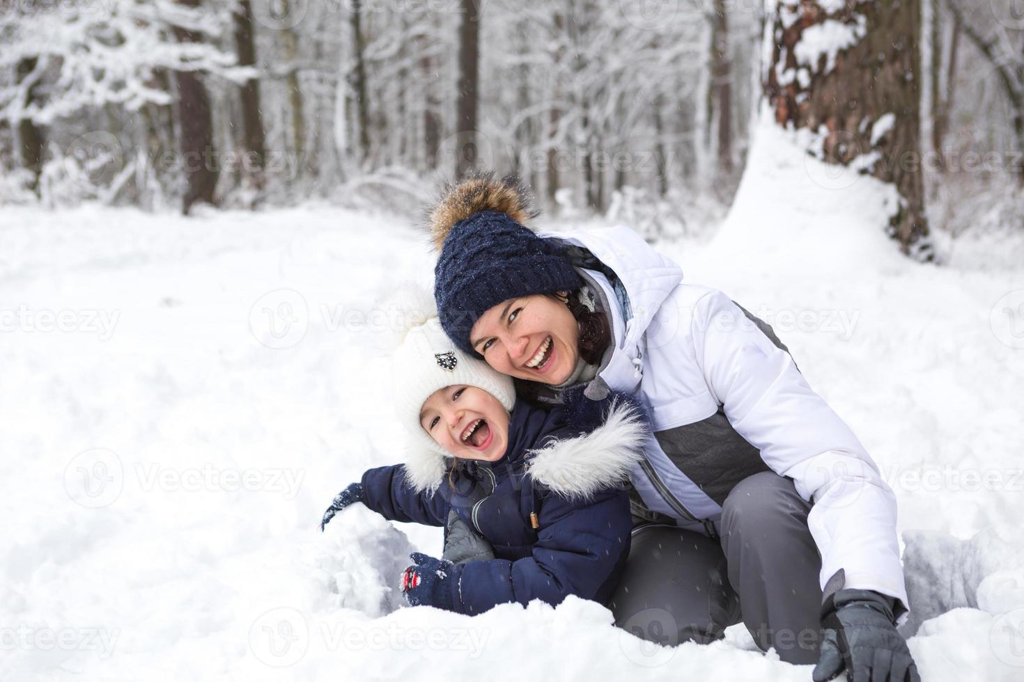 maman et fille jouent à des jeux de neige, construisent une forteresse, font des boules de neige. divertissement d'hiver à l'extérieur, loisirs actifs, plaisir dans le froid dans des vêtements chauds. loisirs de plein air, enfance amusante, famille forte photo