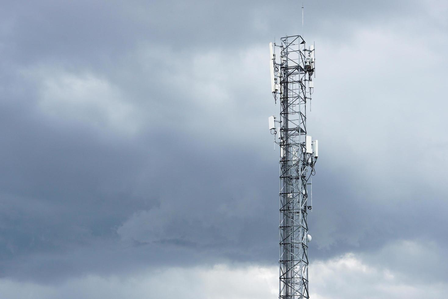 concept de communication et de technologie. tour de télécommunication de la station de base de téléphonie cellulaire, tour de télécommunication sans fil de l'émetteur avec nuages noirs dans le ciel ou couvert. photo