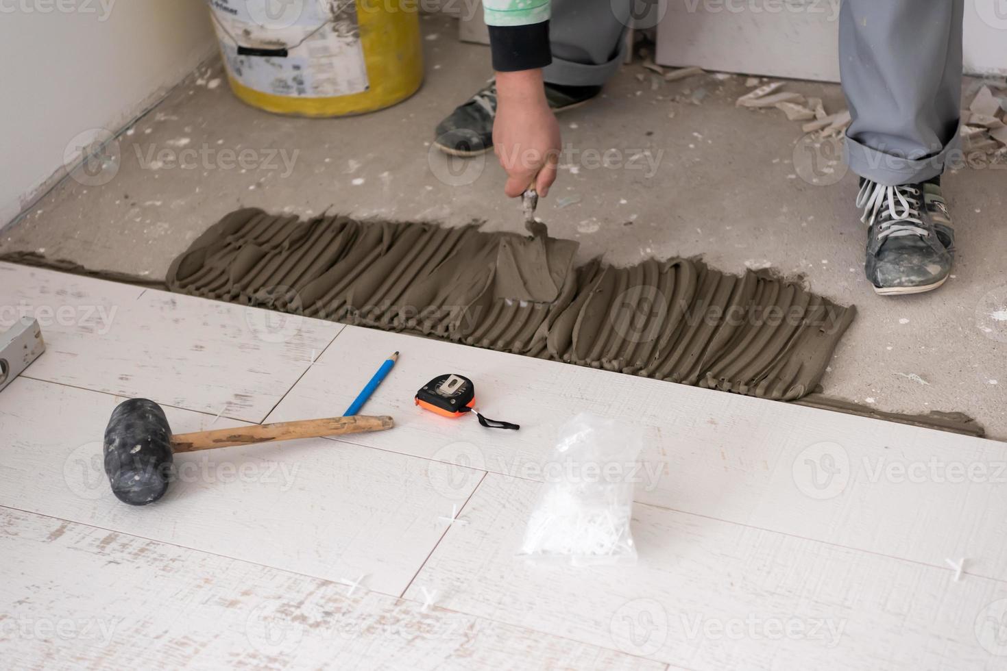 travailleur installant les carreaux en céramique effet bois sur le sol photo