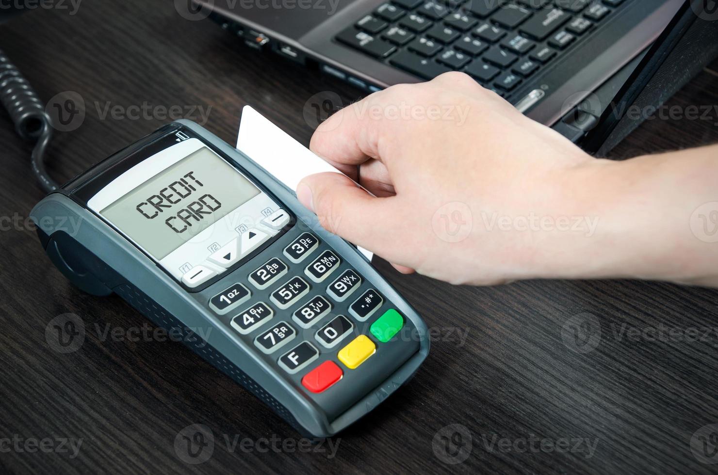 l'homme paie par carte de crédit. glisser la carte en plastique dans le terminal photo
