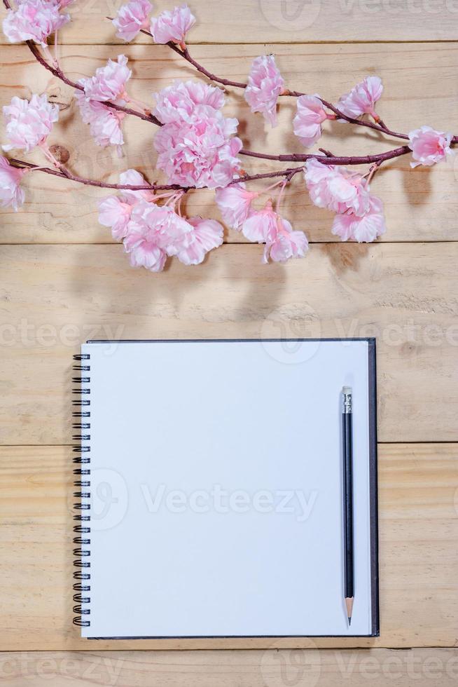 carnet de notes ouvert avec des fleurs de sakura rose sur fond de bois photo