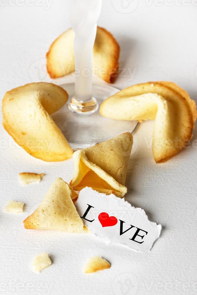 biscuits en forme de tortellini avec le mot amour écrit sur un papier et un verre de champagne.image verticale. photo