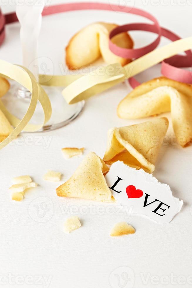 biscuits en forme de tortellini avec le mot amour écrit sur un papier et une coupe de champagne avec banderoles.image verticale. photo
