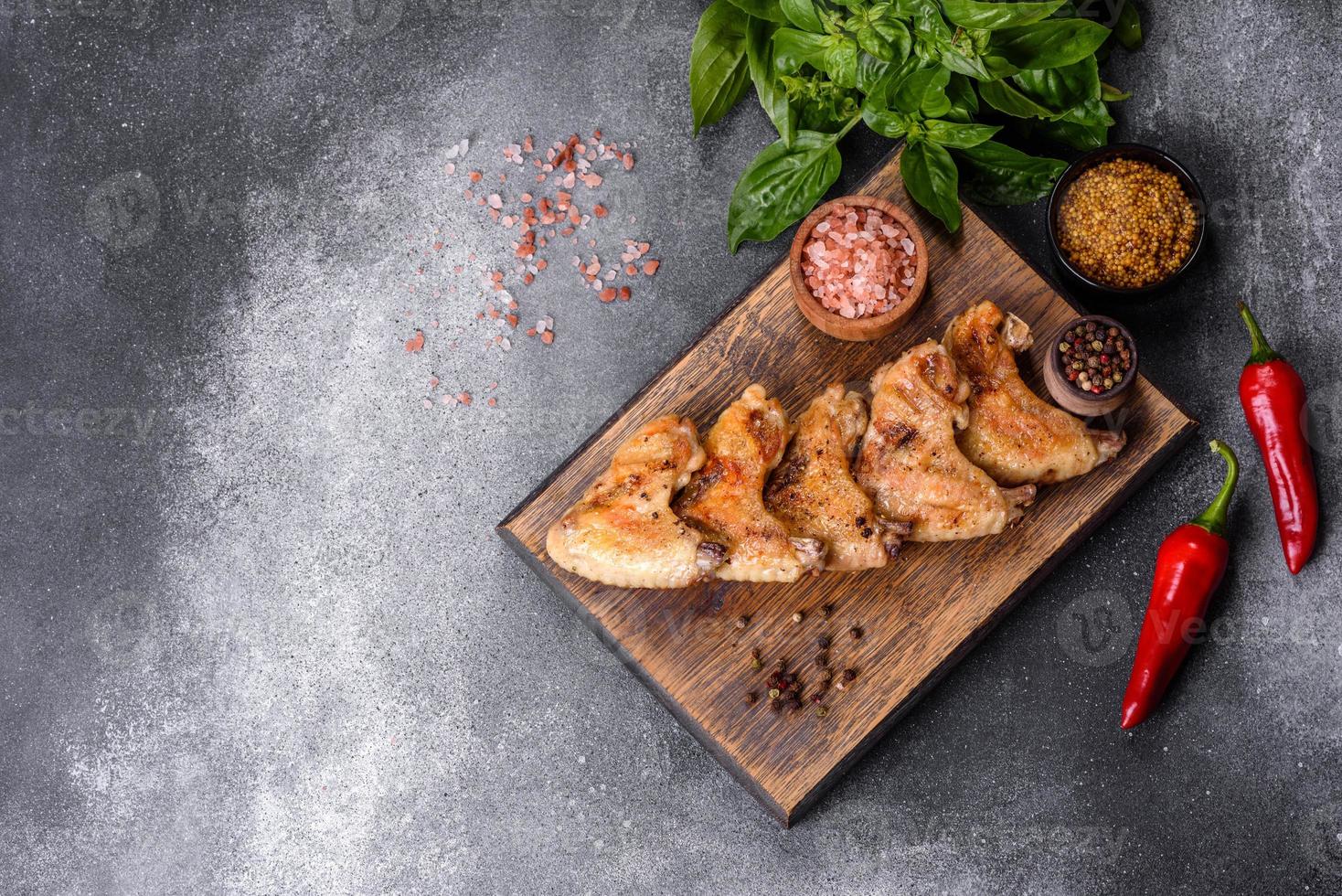 Ailes de poulet cuites au four avec graines de sésame et sauce sur une planche à découper en bois photo