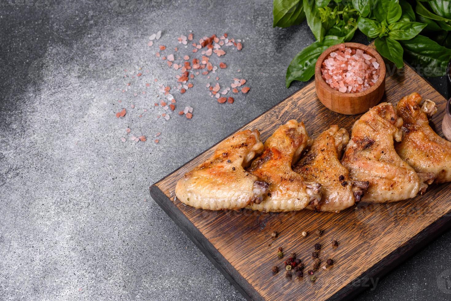 Ailes de poulet cuites au four avec graines de sésame et sauce sur une planche à découper en bois photo