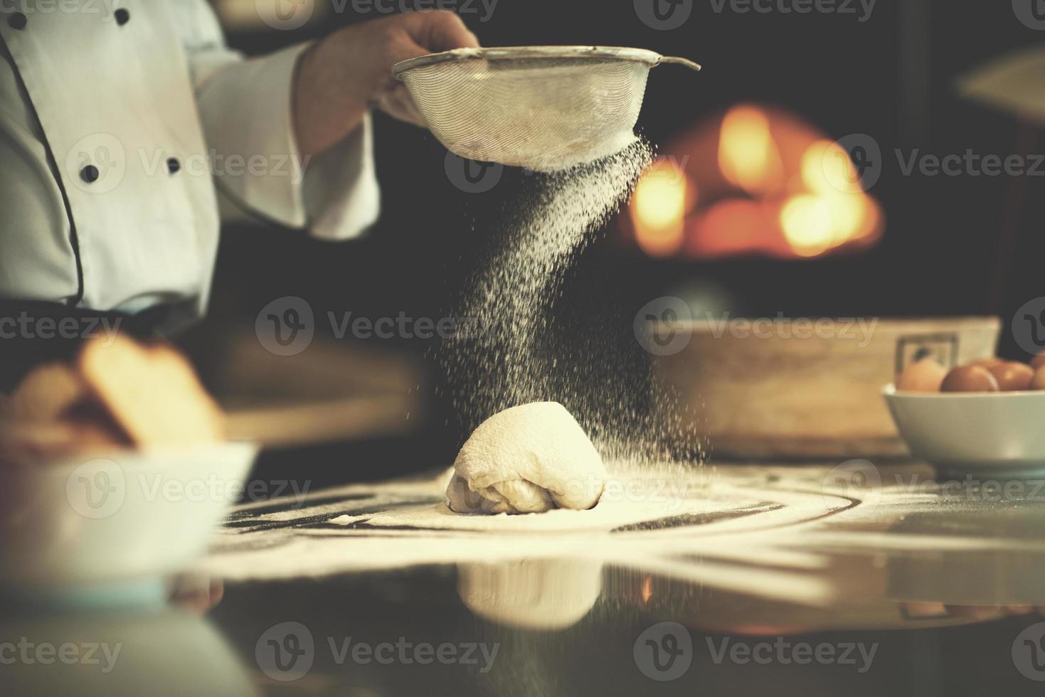 chef saupoudrant de farine sur la pâte à pizza fraîche photo