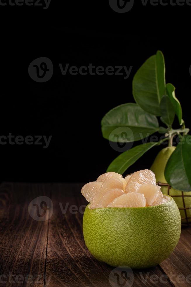 pomelo frais, pomelo, pamplemousse, shaddock sur table en bois sur fond noir, gros plan, espace de copie. fruits pour le festival de la mi-automne. photo