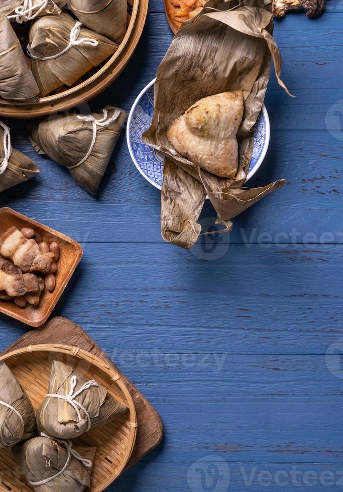 concept de festival de bateaux-dragons - boulette de riz, zongzi, cuisine chinoise traditionnelle sur fond de bois bleu pour le festival duanwu, vue de dessus, concept de conception à plat. photo