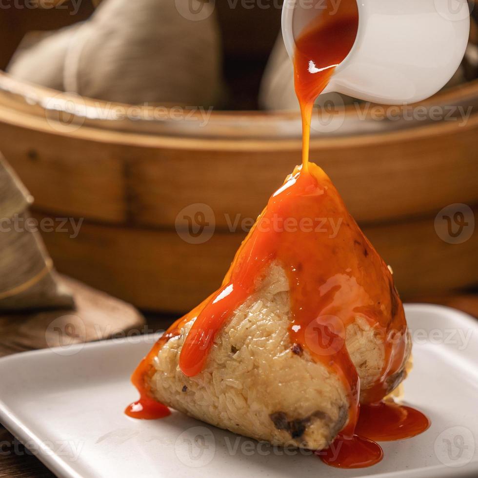 manger du zongzi - boulette de riz du festival du bateau-dragon jeune femme asiatique mangeant de la nourriture traditionnelle chinoise sur une table en bois à la maison célébration, gros plan photo