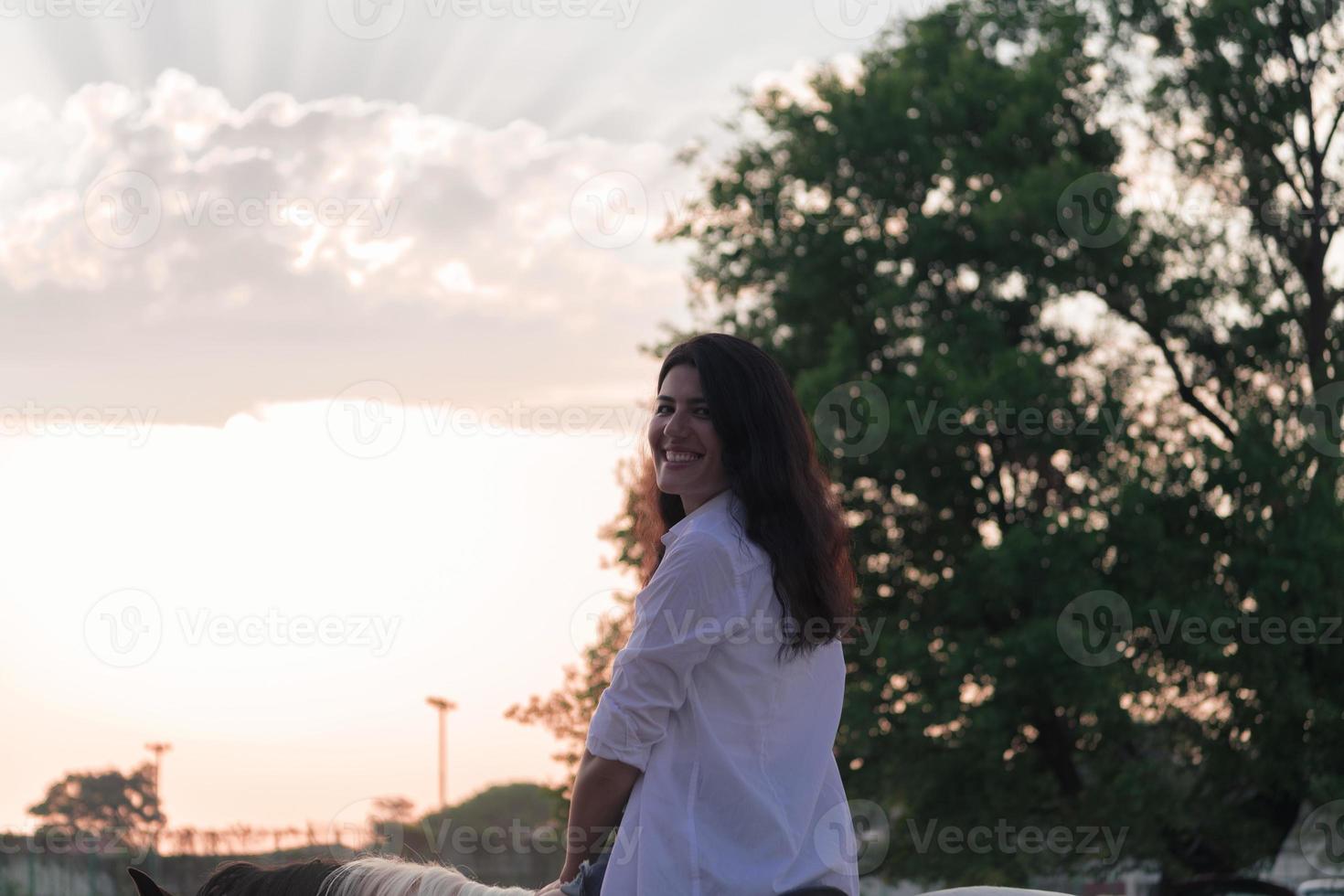 femme en vêtements d'été aime monter à cheval sur une belle plage de sable au coucher du soleil. mise au point sélective photo