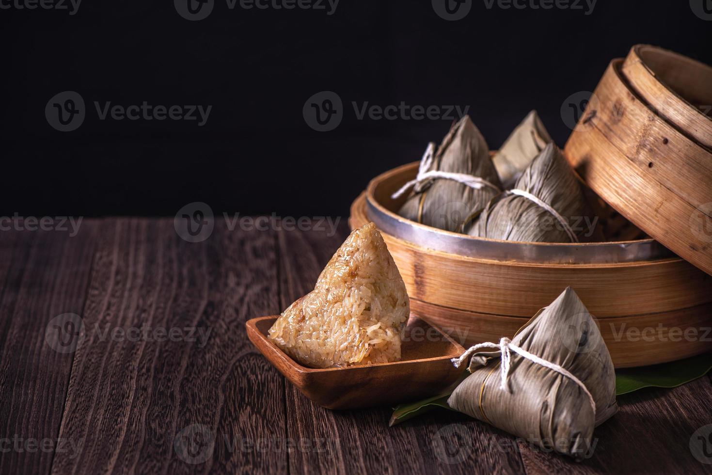 boulette de riz, zongzi - tas de plats cuisinés traditionnels chinois sur une table en bois sur fond noir, concept de festival de bateaux-dragons, gros plan, espace de copie photo