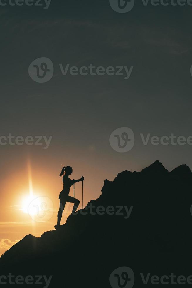 femme grimpe parmi les rochers dans un coucher de soleil de montagne coloré photo