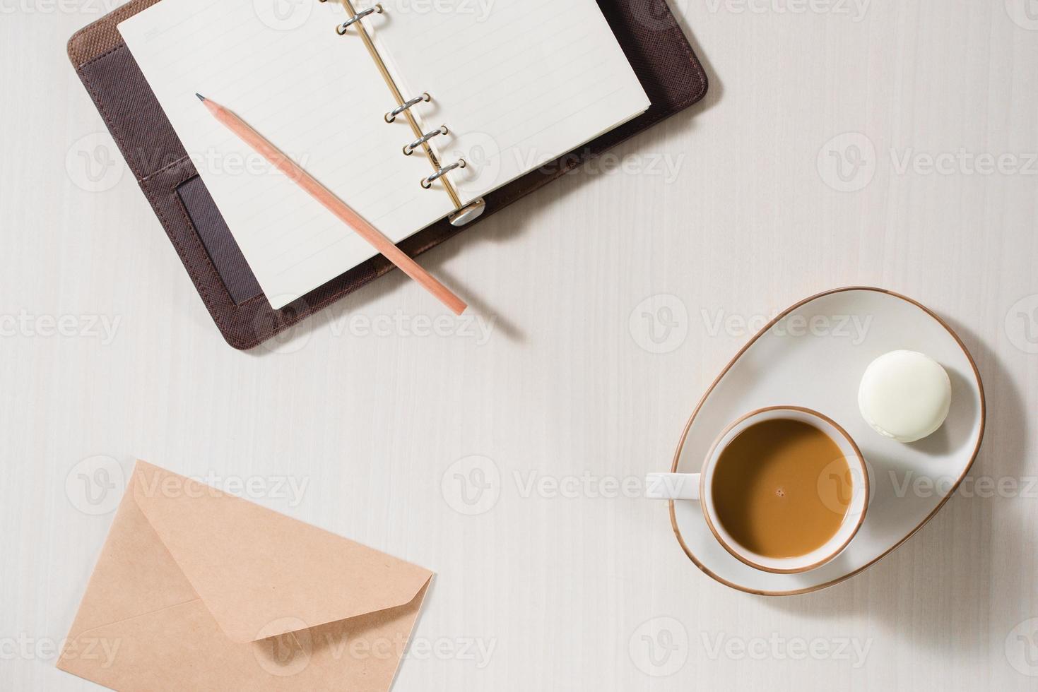 cahier propre, tasse de café et macaron coloré sur la vue de dessus de bureau gris. petit déjeuner confortable le matin. mise à plat de la mode. macarons sucrés. photo