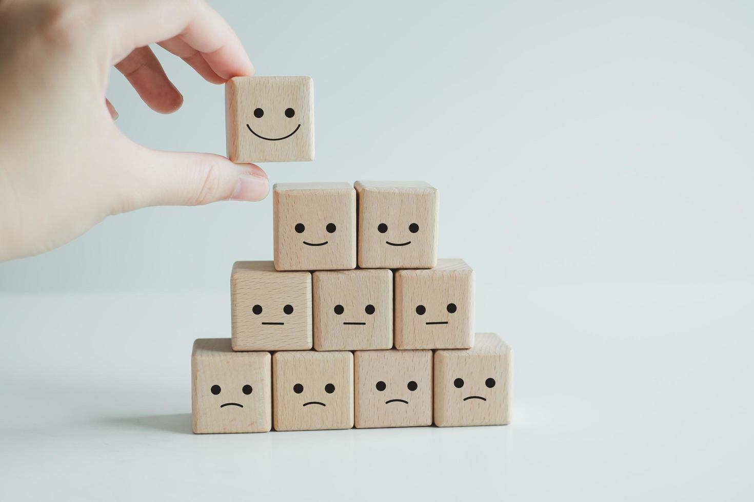 concepts d'évaluation du service client et d'enquête de satisfaction. la main du client a choisi le symbole du visage souriant du visage heureux sur des blocs de bois. photo