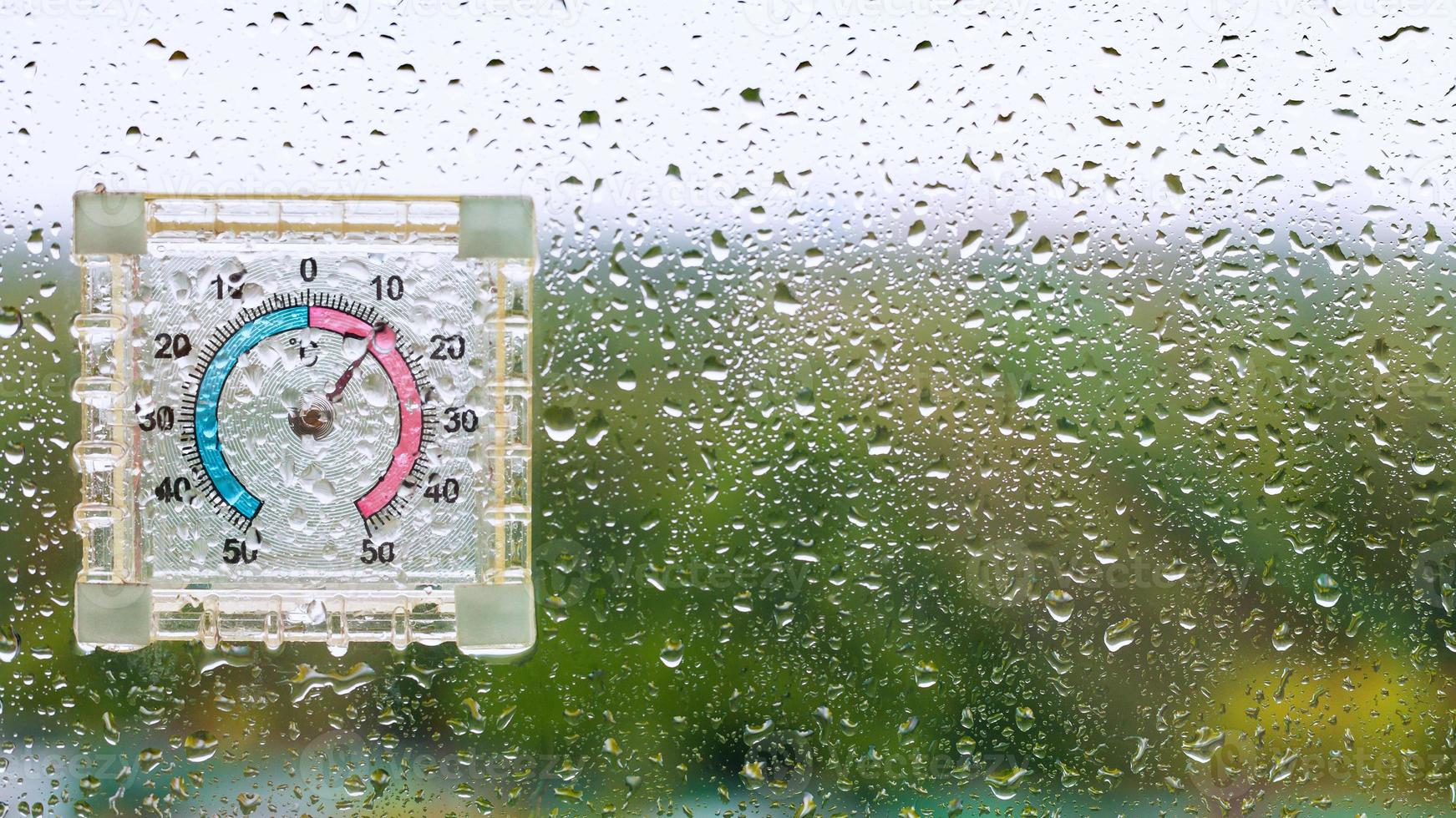 gouttes de pluie et thermomètre humide extérieur sur verre photo