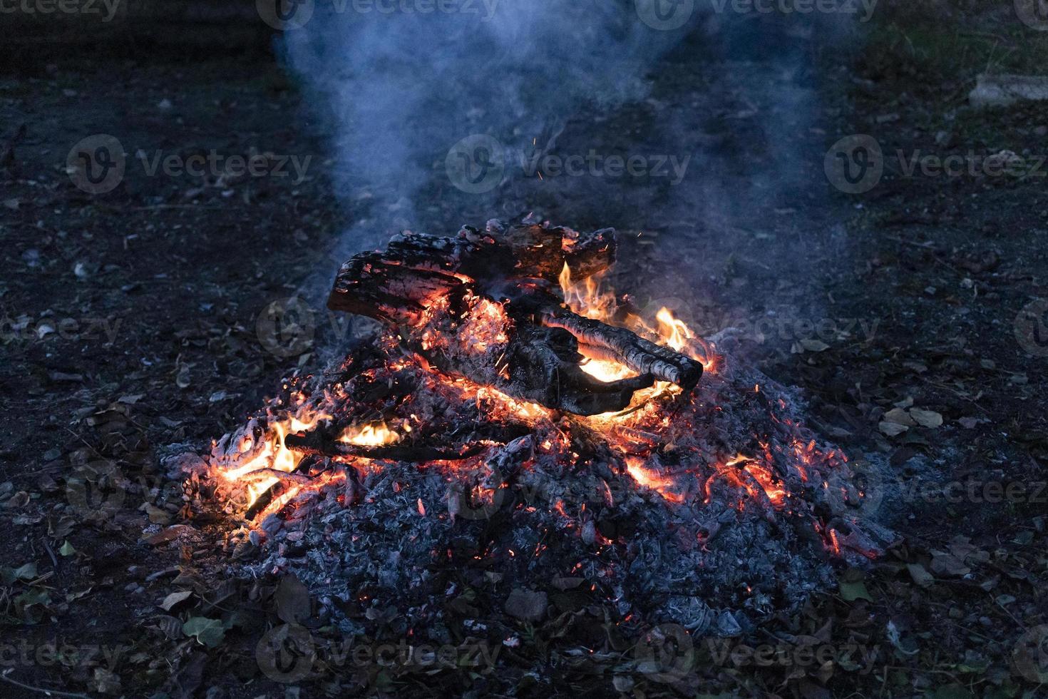 bois de chauffage fumant sur des cendres dans le crépuscule bleu photo